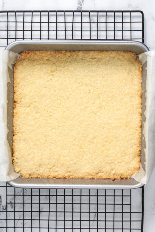 A baked shortbread crust in a square baking dish.