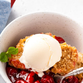 Cherry cobbler in a bowl with a spoon.
