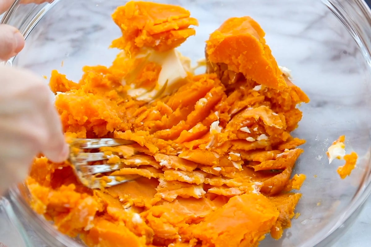 Mashed sweet potatoes in a bowl with butter.