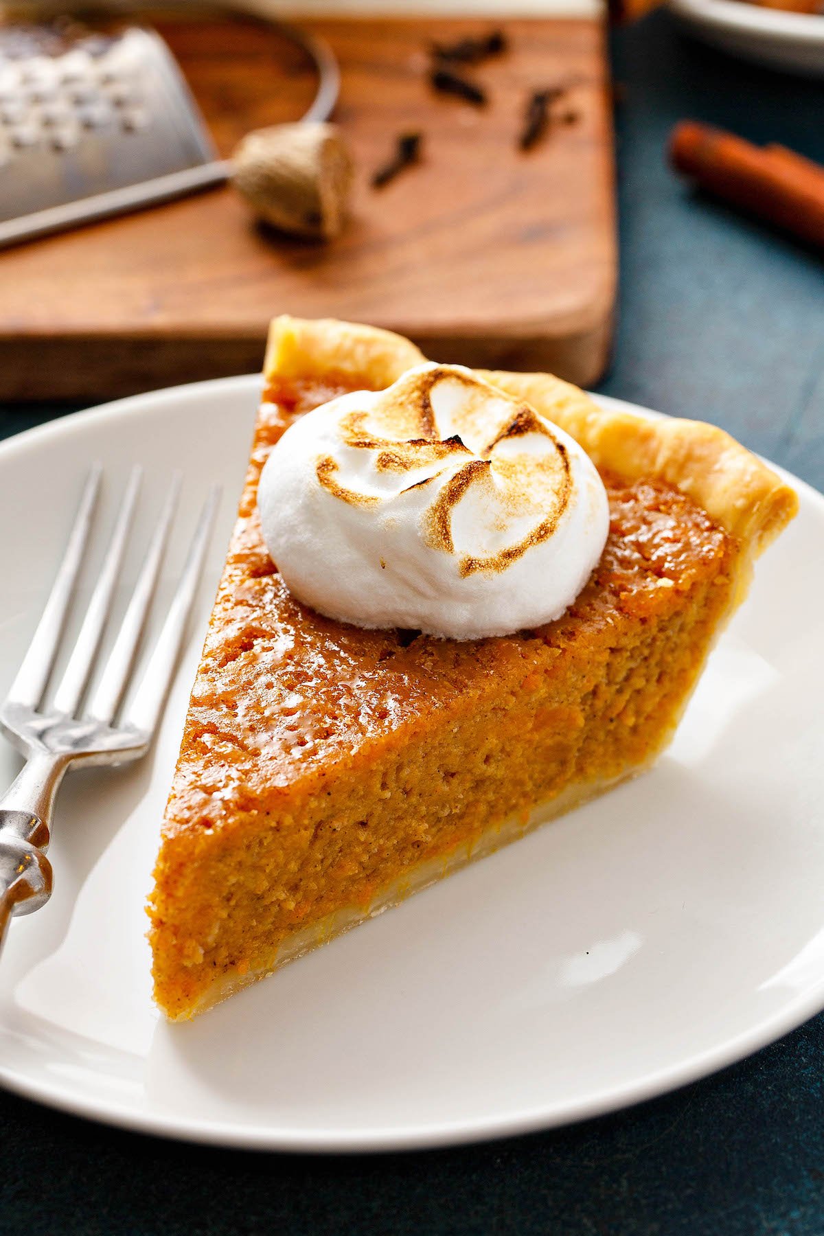 An up close image of sweet potato pie on a white plate with a fork.