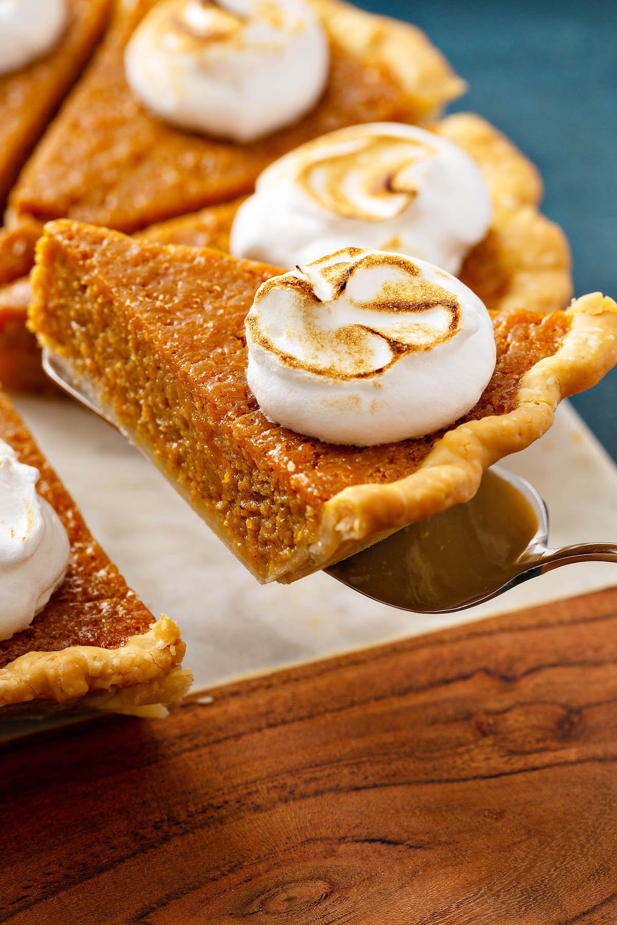 A slice of sweet potato pie being picked up by a pie server.