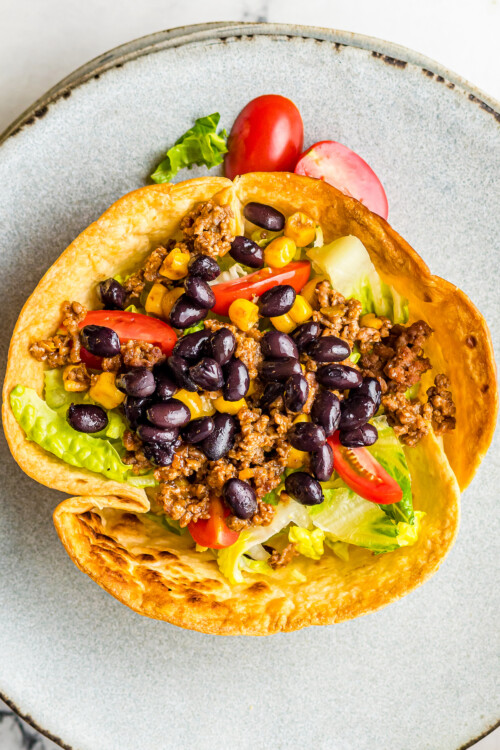 A tortilla bowl filled with taco salad ingredients.