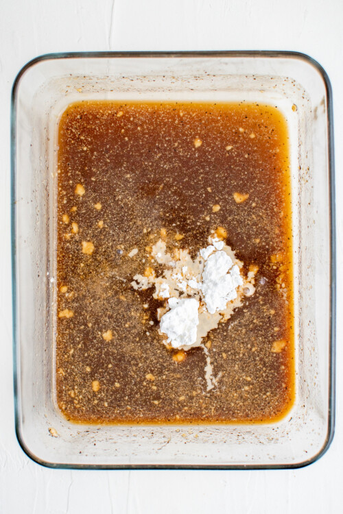 A rectangular glass pan of leftover marinade, with cornstarch added.