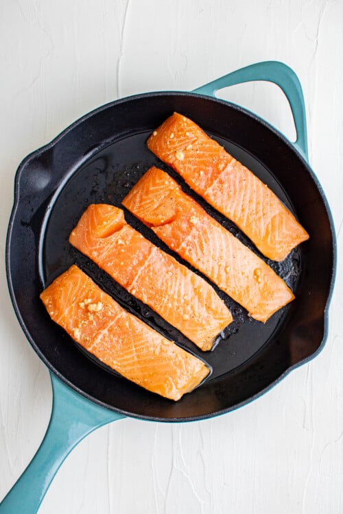 Salmon filets sauteing in a heavy pan.