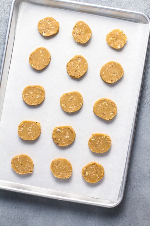 Unbaked cookies lined up on a baking sheet.