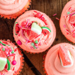 Close up top view of pink frosted watermelon cupcakes decorated with sprinkles and watermelon candy.