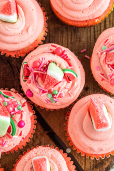 Close up top view of pink frosted watermelon cupcakes decorated with sprinkles and watermelon candy.