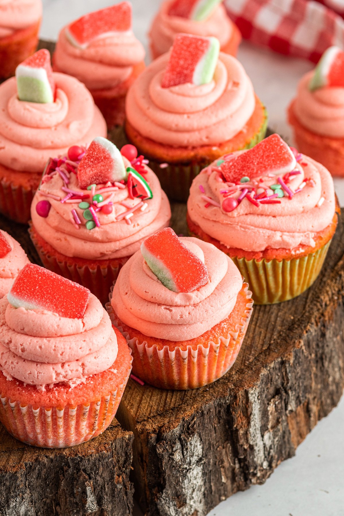 Pink frosted and decorated watermelon cupcakes on a wooden platter.
