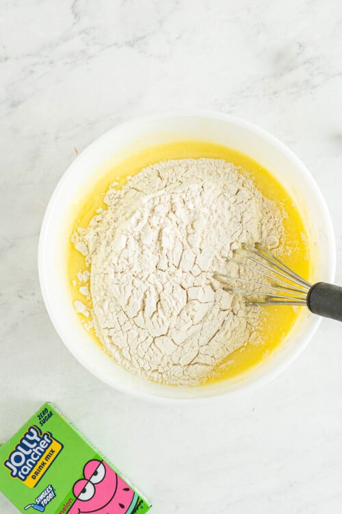 Dry ingredients are added into a mixing bowl to be whisked together with wet ingredients.