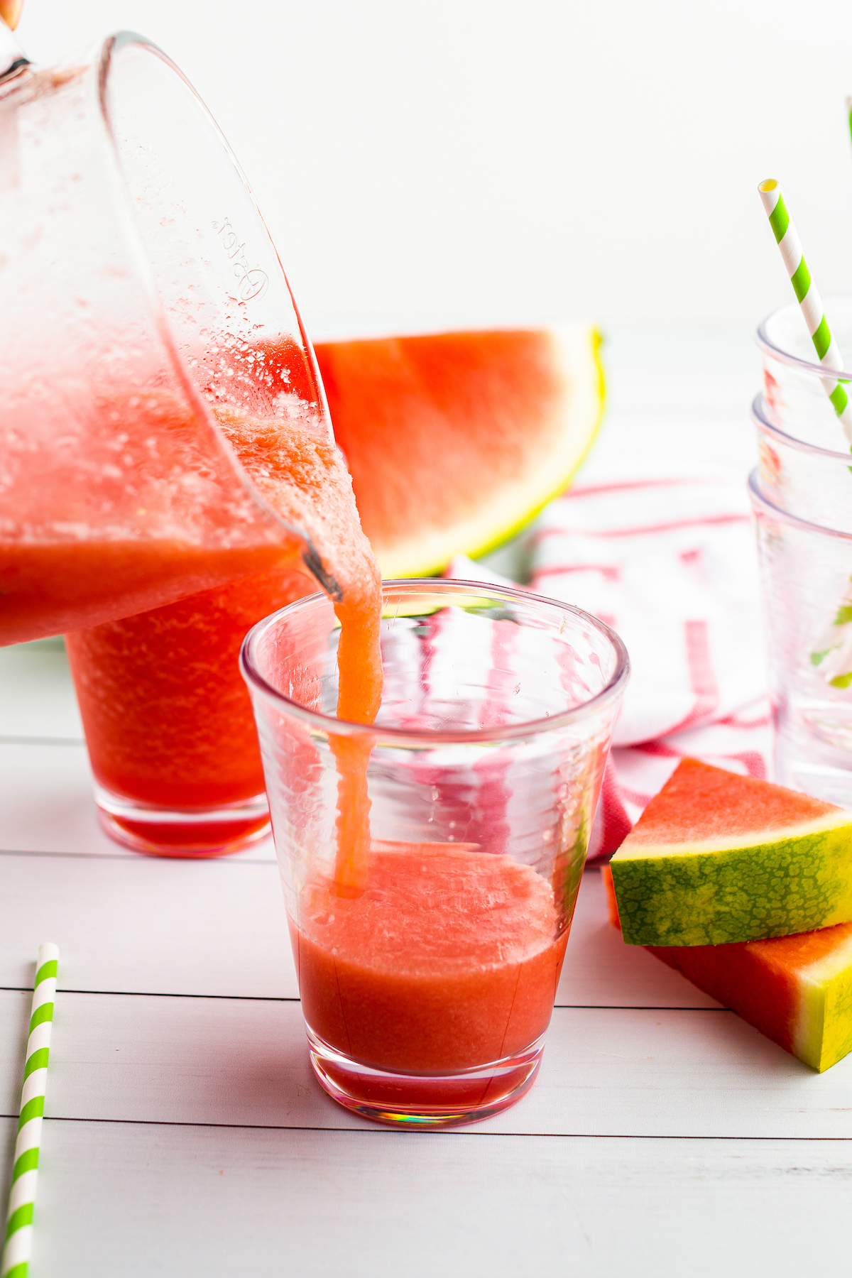 Watermelon limeade slushie is poured from a blender into a glass.