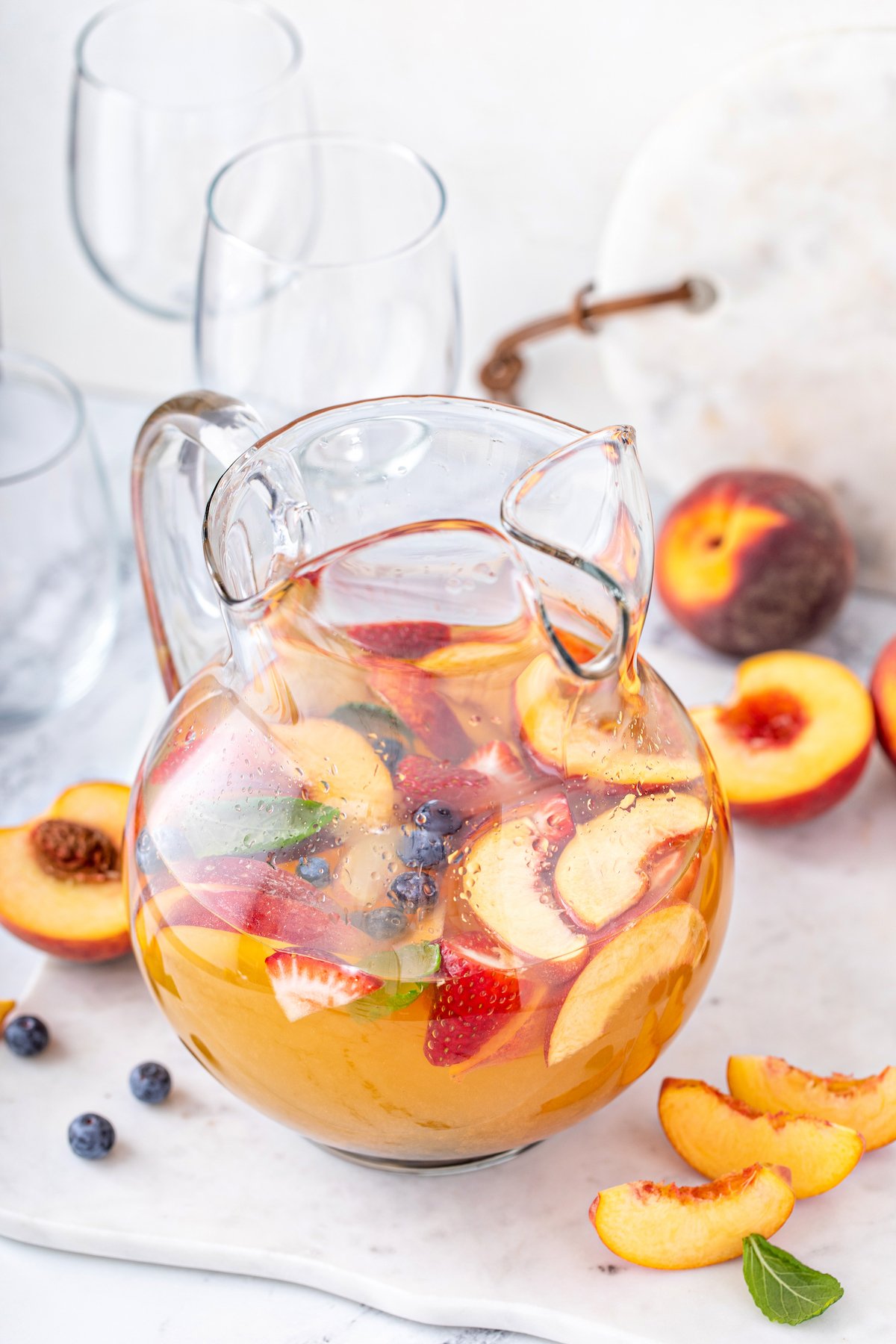 A pitcher of white peach sangria with fresh fruit.