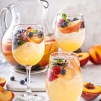 Glasses of white peach sangria with blueberries and strawberries.