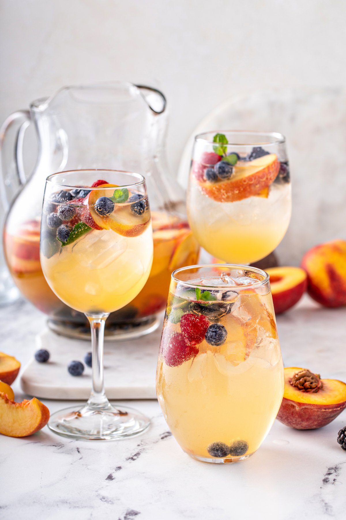 Glasses of white peach sangria with blueberries and strawberries.