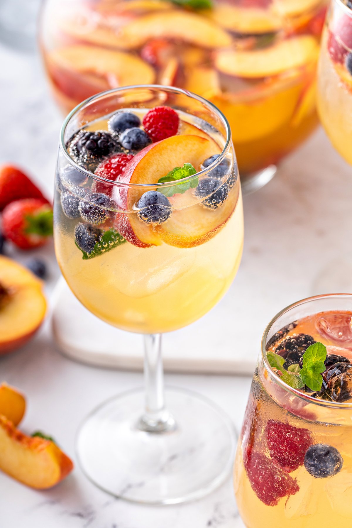 Close-up shot of fizzy white wine cocktail with fruit and ice.