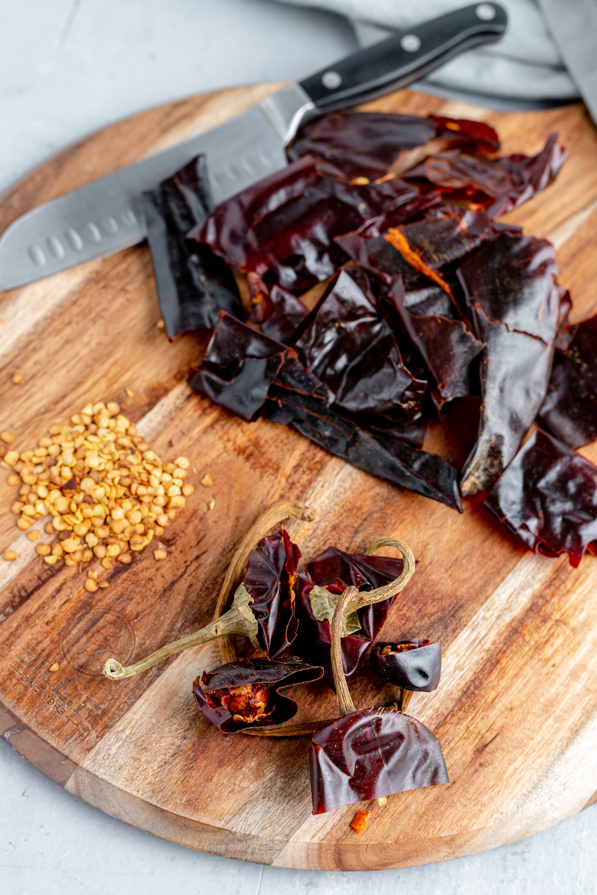 A cutting board with dried chilies, chili seeds, and chili tops separated neatly into groups.