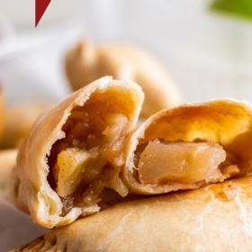 Apple empanadas stacked on top of each other with one broken in half to show the inside.
