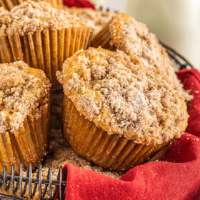 Close-up shot of muffins in a wire basket with a red cloth napkin.
