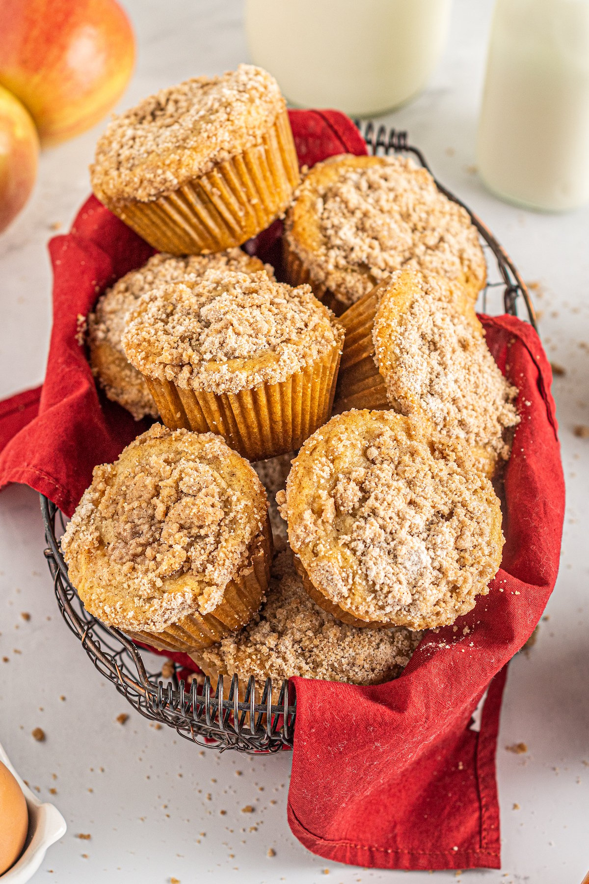 Crumb-topped muffins in a basket lined with a red tea towel.