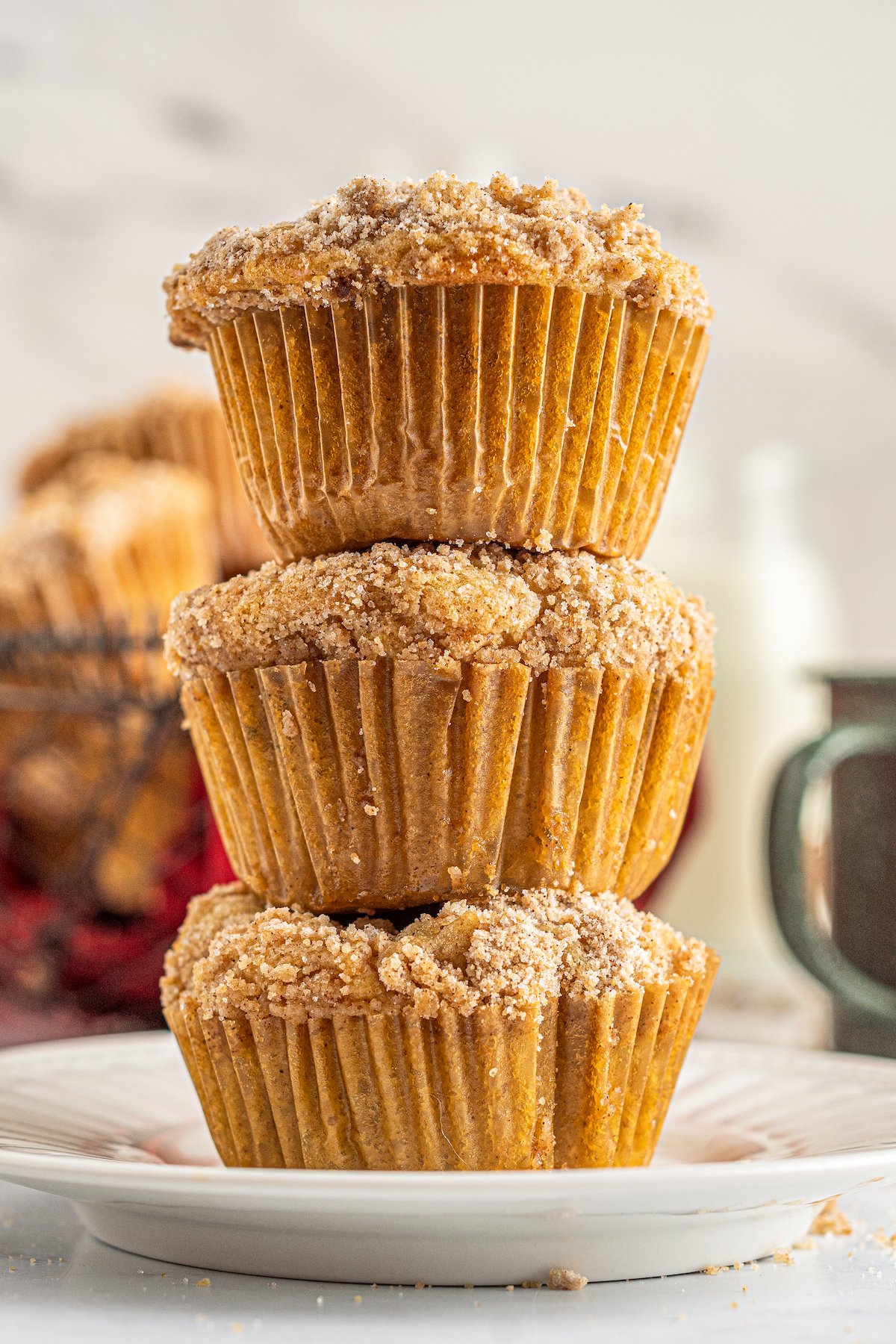 Three apple cinnamon muffins stacked on top of each other on a small plate.