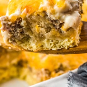 A slice of biscuits and gravy breakfast casserole on a wooden spoon.