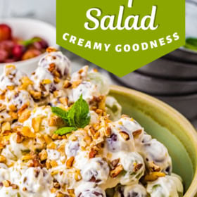 A bowl with creamy grape salad topped with chopped nuts and toffee bits.