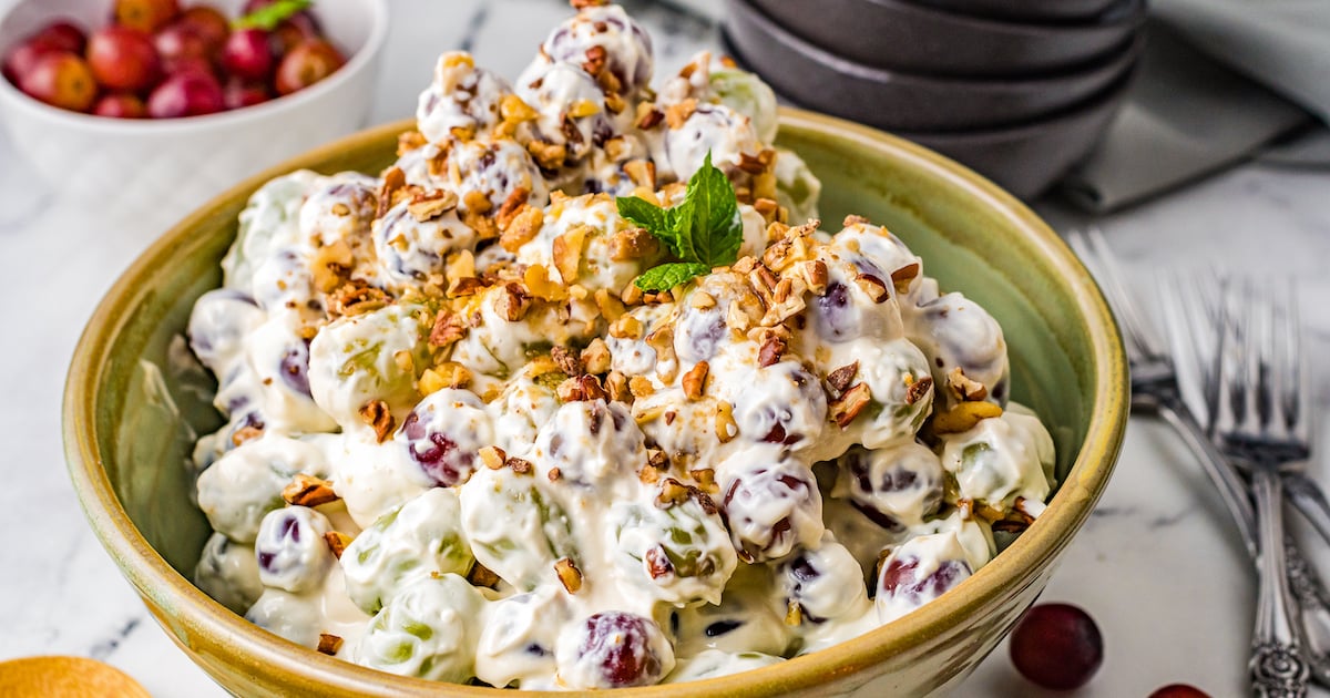 A bowl with creamy grape salad with toffee and pecans on top.