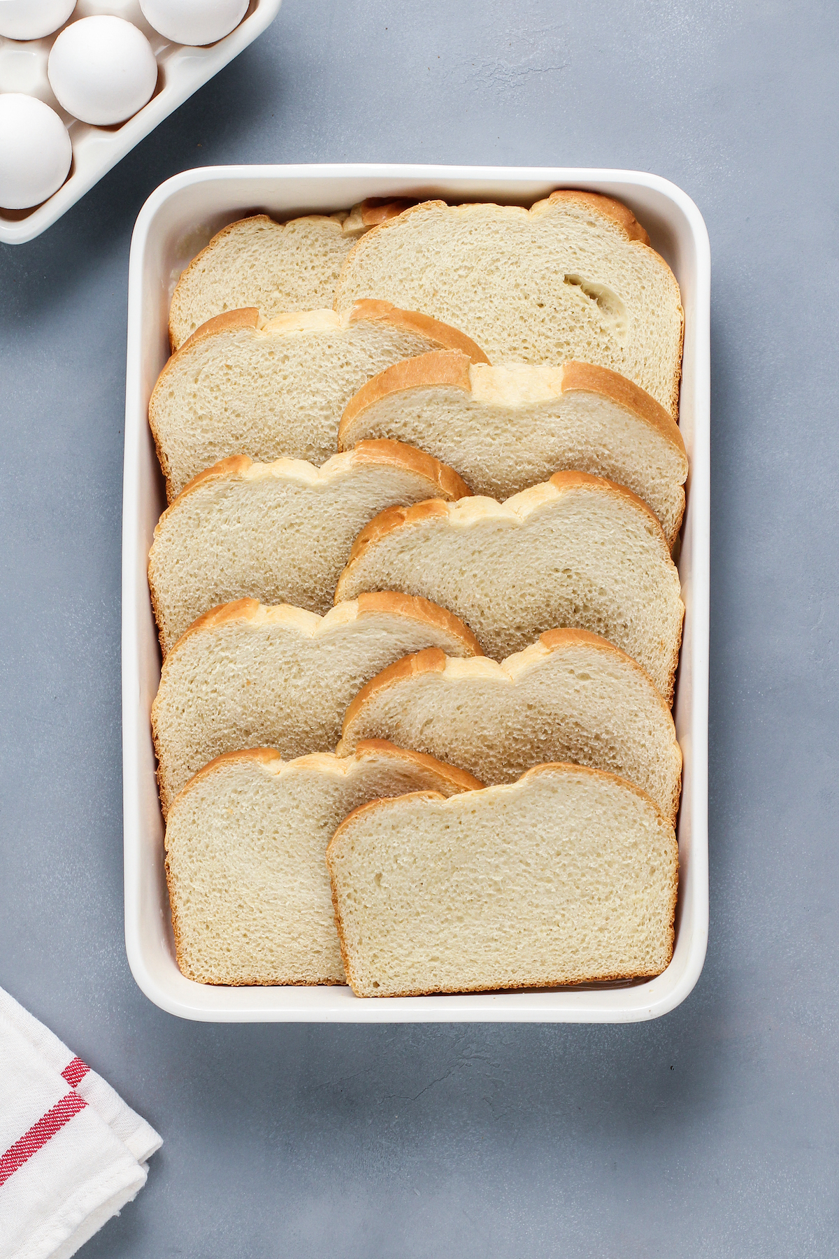 A large rectangular baking dish, filled with overlapping slices of bread.