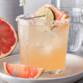 Grapefruit cocktail in a glass on a white plate.