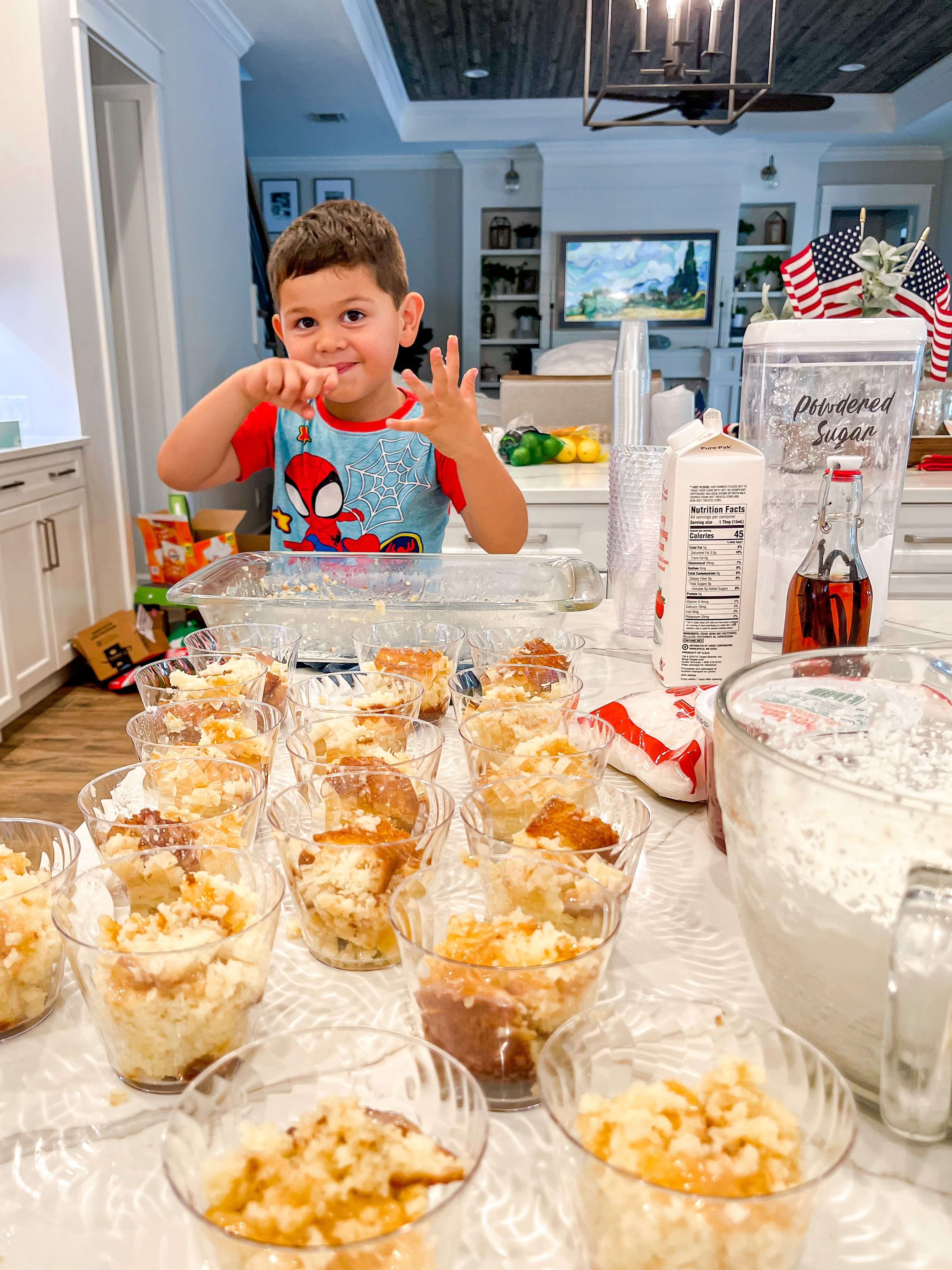 Milo helping make cups with coconut tres leche cake in them.