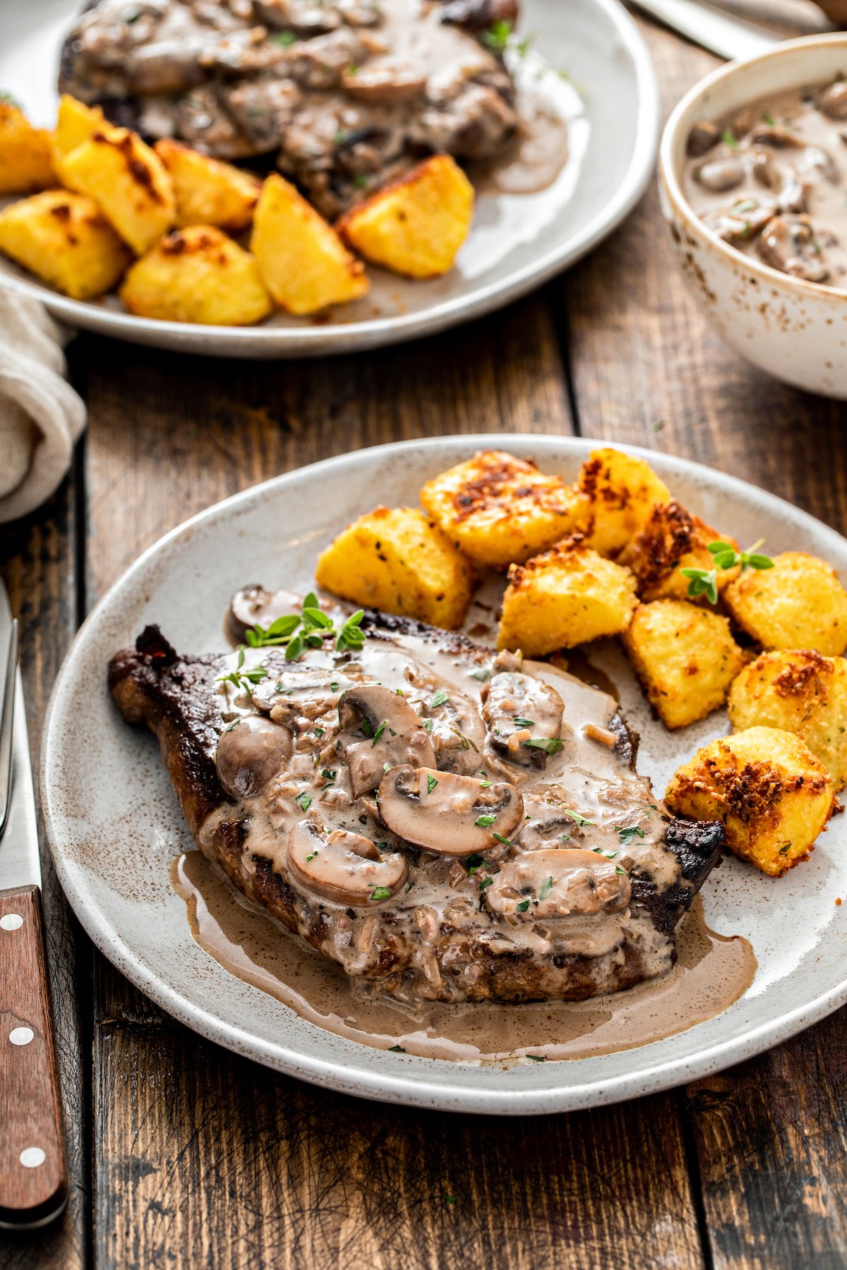 A steak dinner with mushrooms in cream sauce.