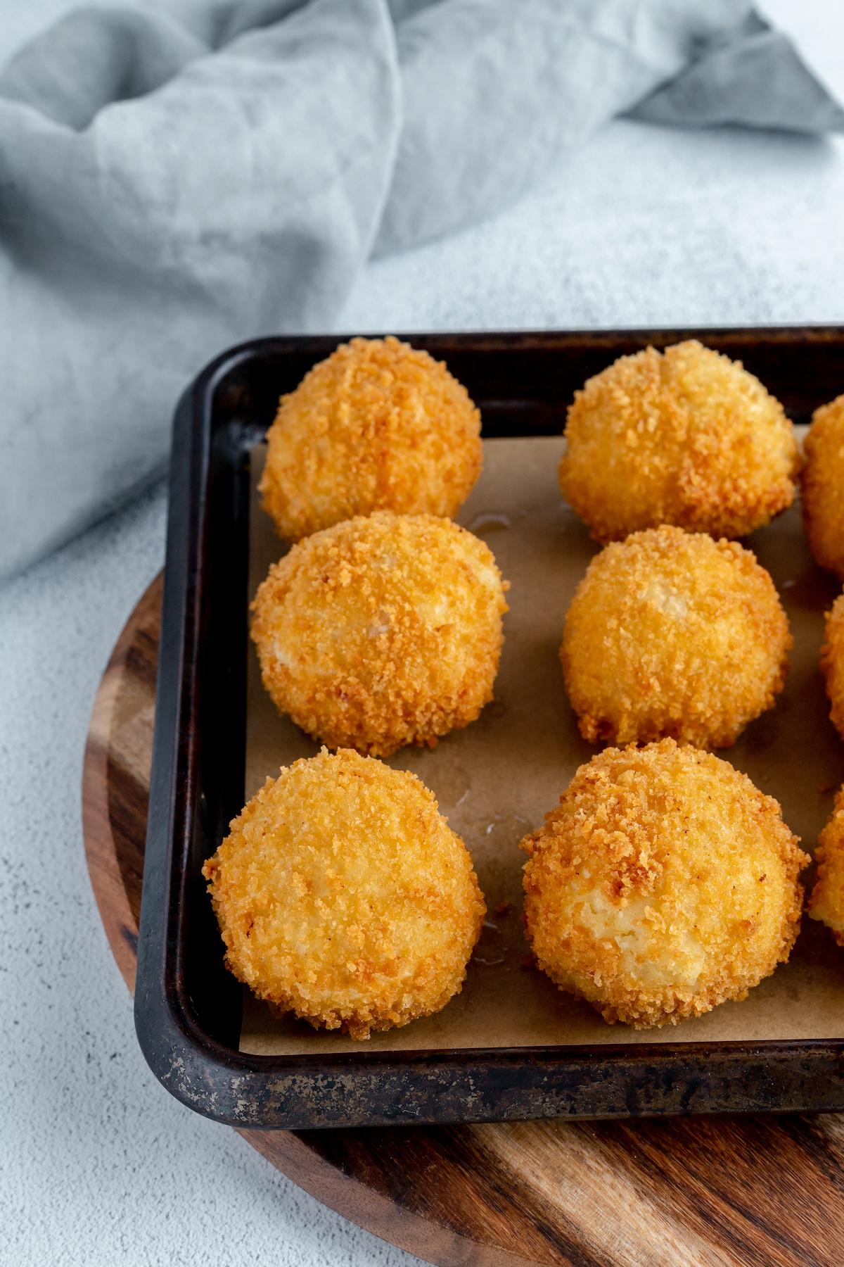 A baking sheet with fried, stuffed mashed potatoes lined up on it.