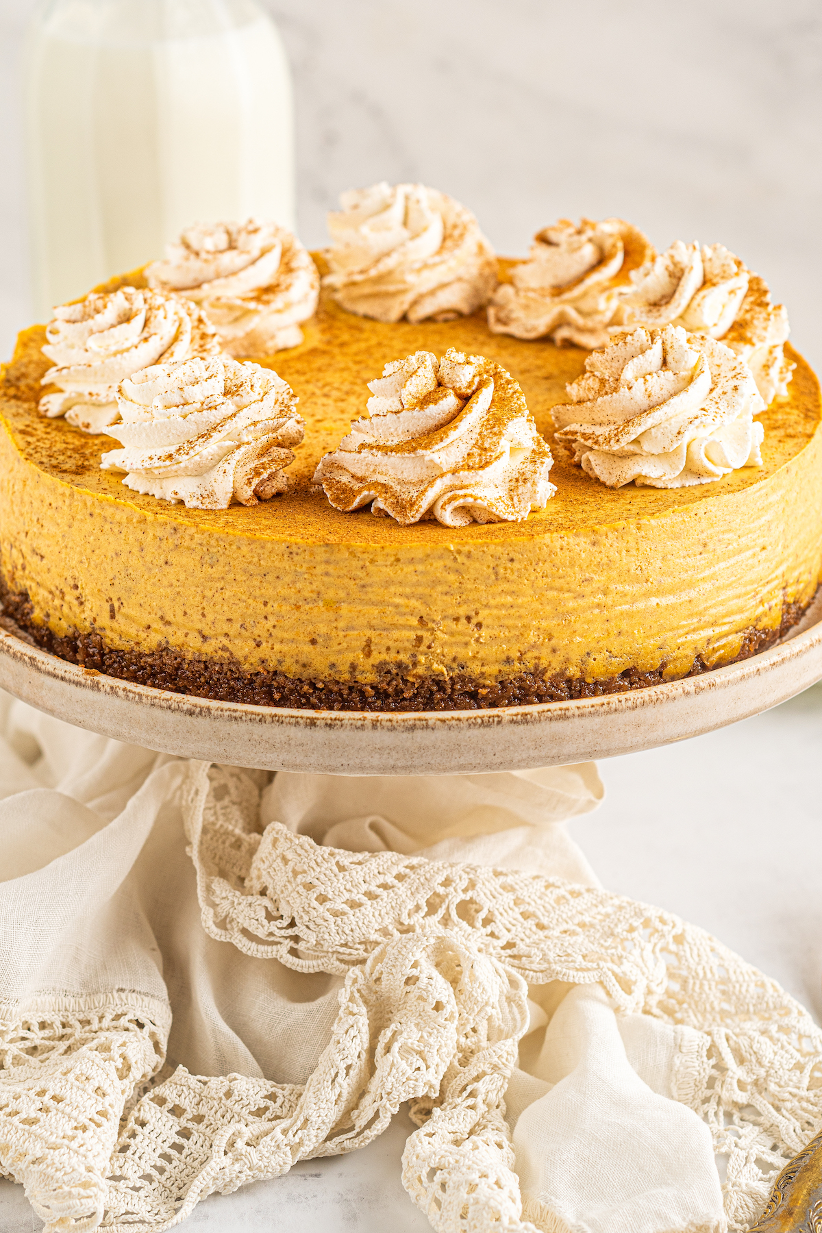 Pumpkin cheesecake garnished with piped whipped cream and ground cinnamon.