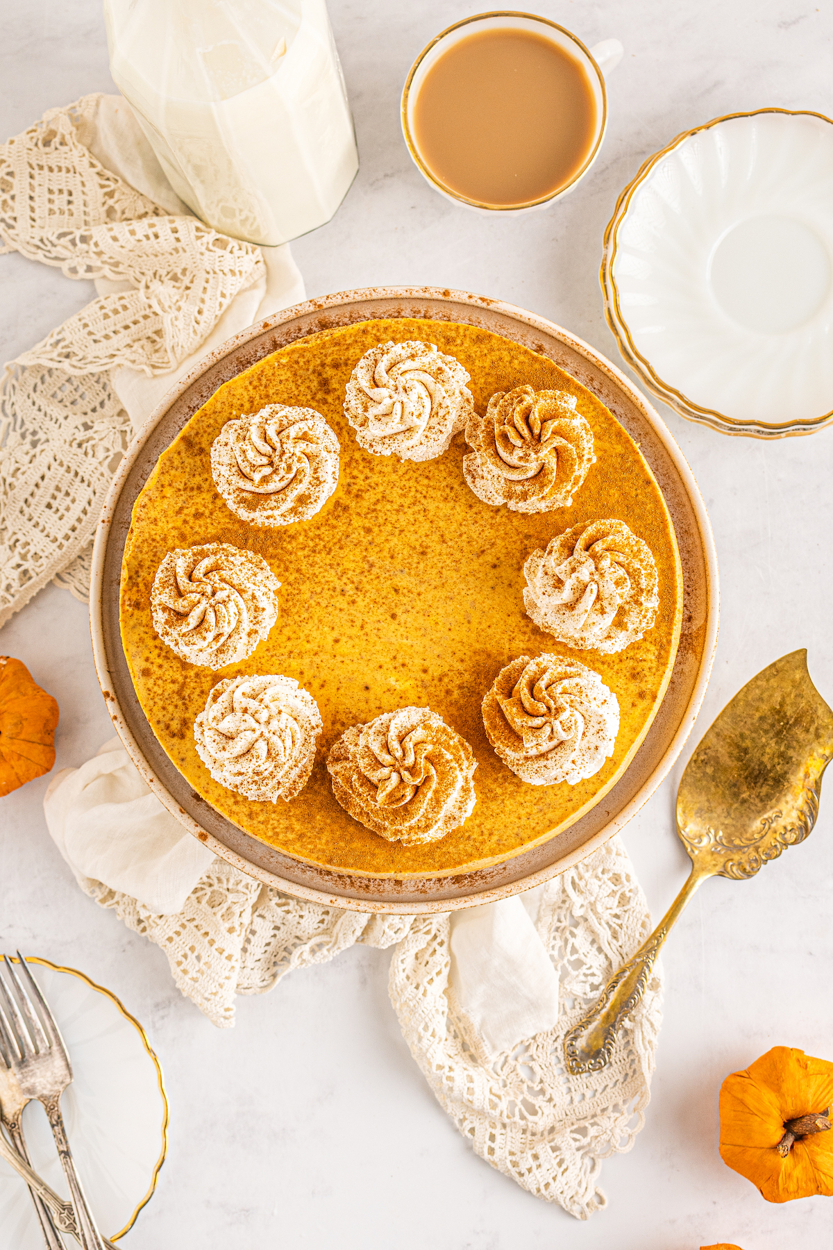 Overhead shot of a pumpkin-spice cheesecake topped with cinnamon and piped whipped cream.