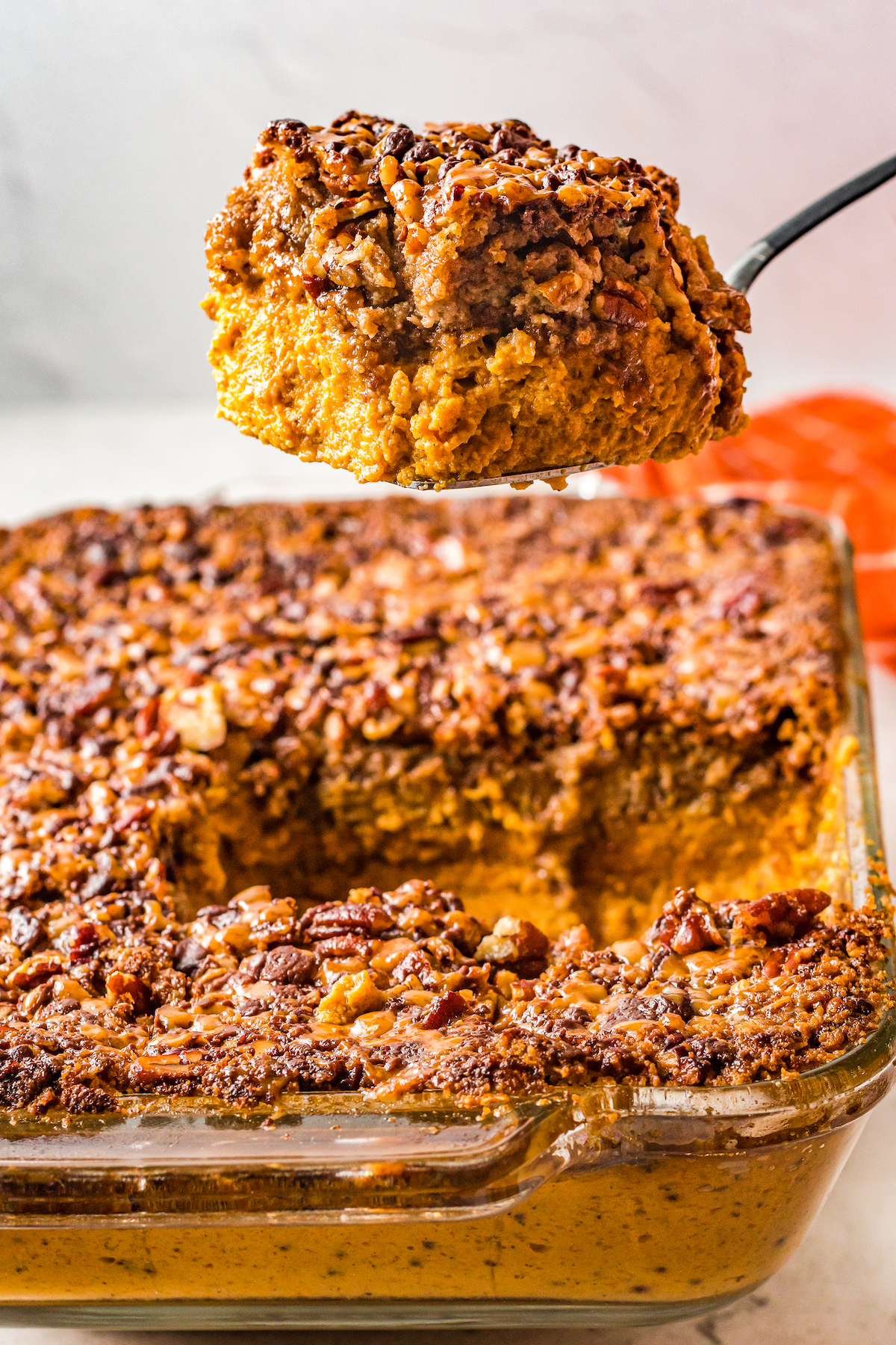 A cake server lifting a square of pumpkin dump cake out of the pan.