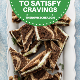 Cucumber sandwiches on marble pumpernickle bread sliced into triangles on a white serving platter.