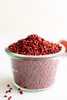 A cup overflowing with bright red annatto seeds.