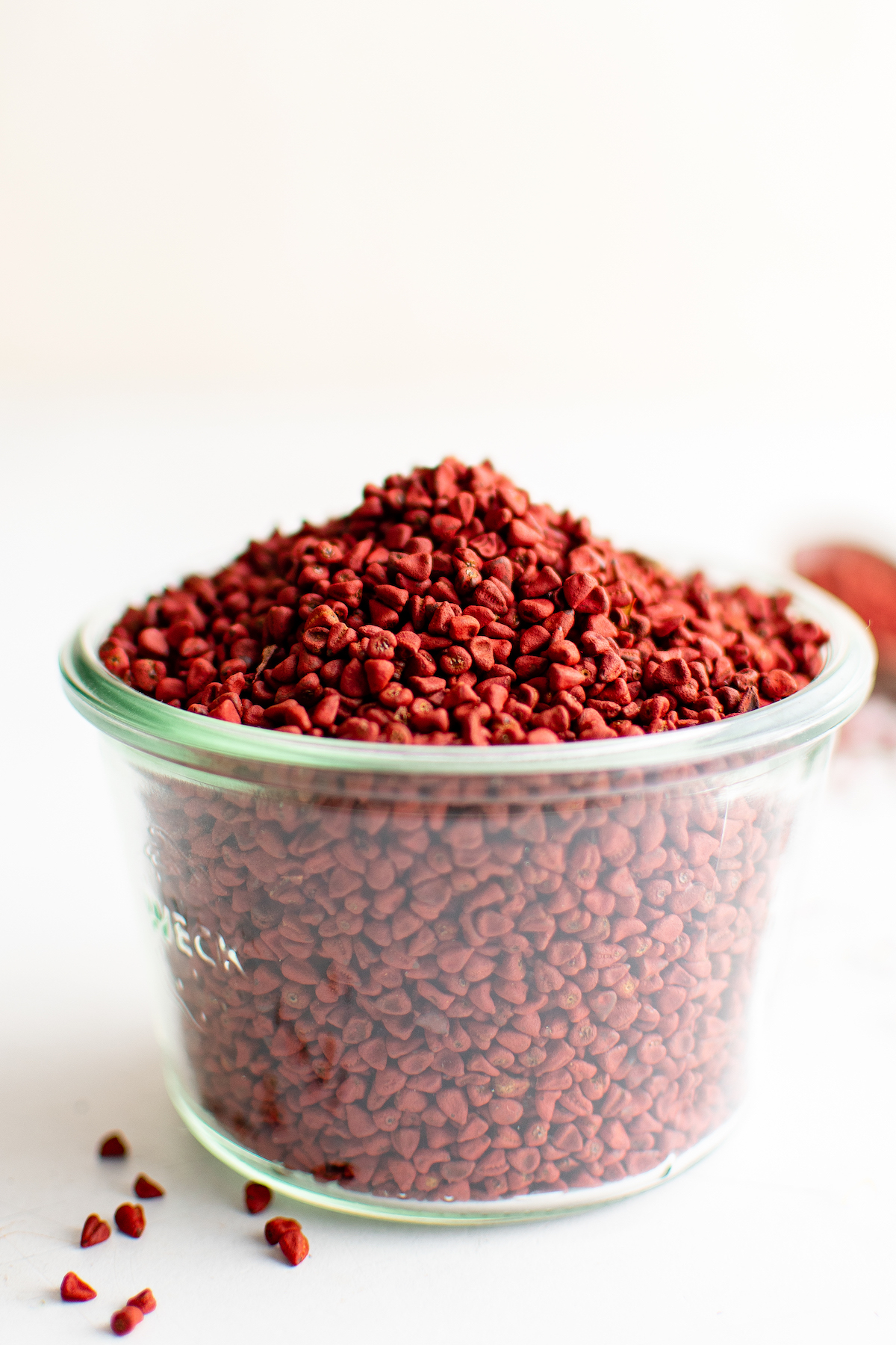 Annatto seeds in a small measuring cup.
