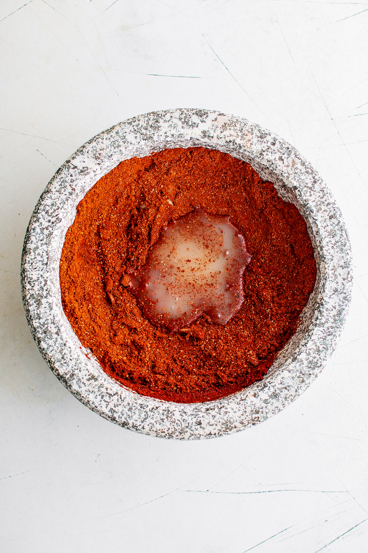 dried spices in a mortar in pestle with a small amount of orange juice