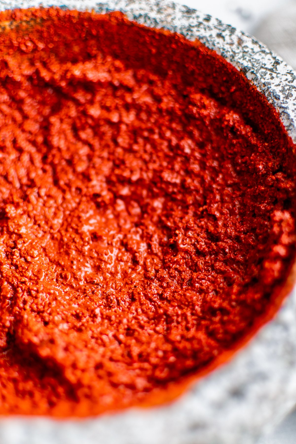 A bright red spice-based meat rub in a mortar and pestle