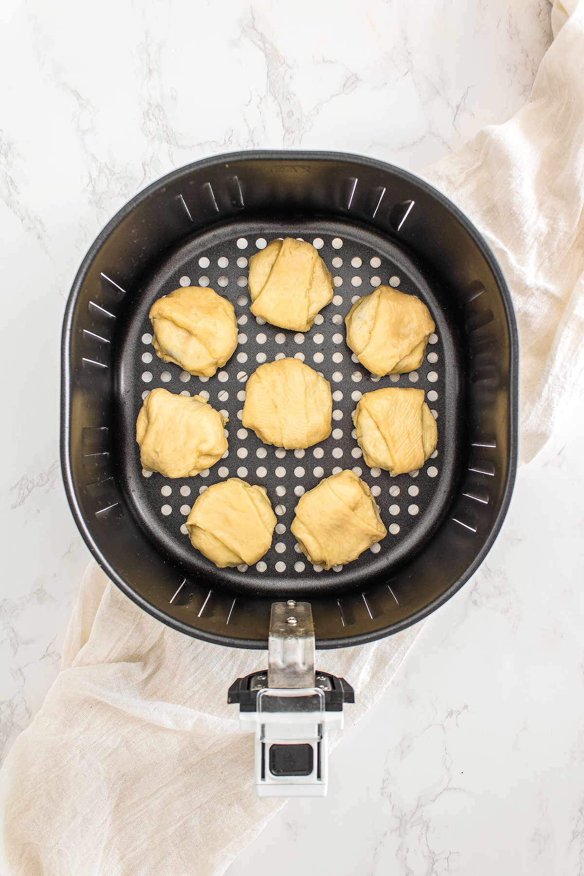top view of an air fryer with eight crescent roll-wrapped Oreos prior to cooking