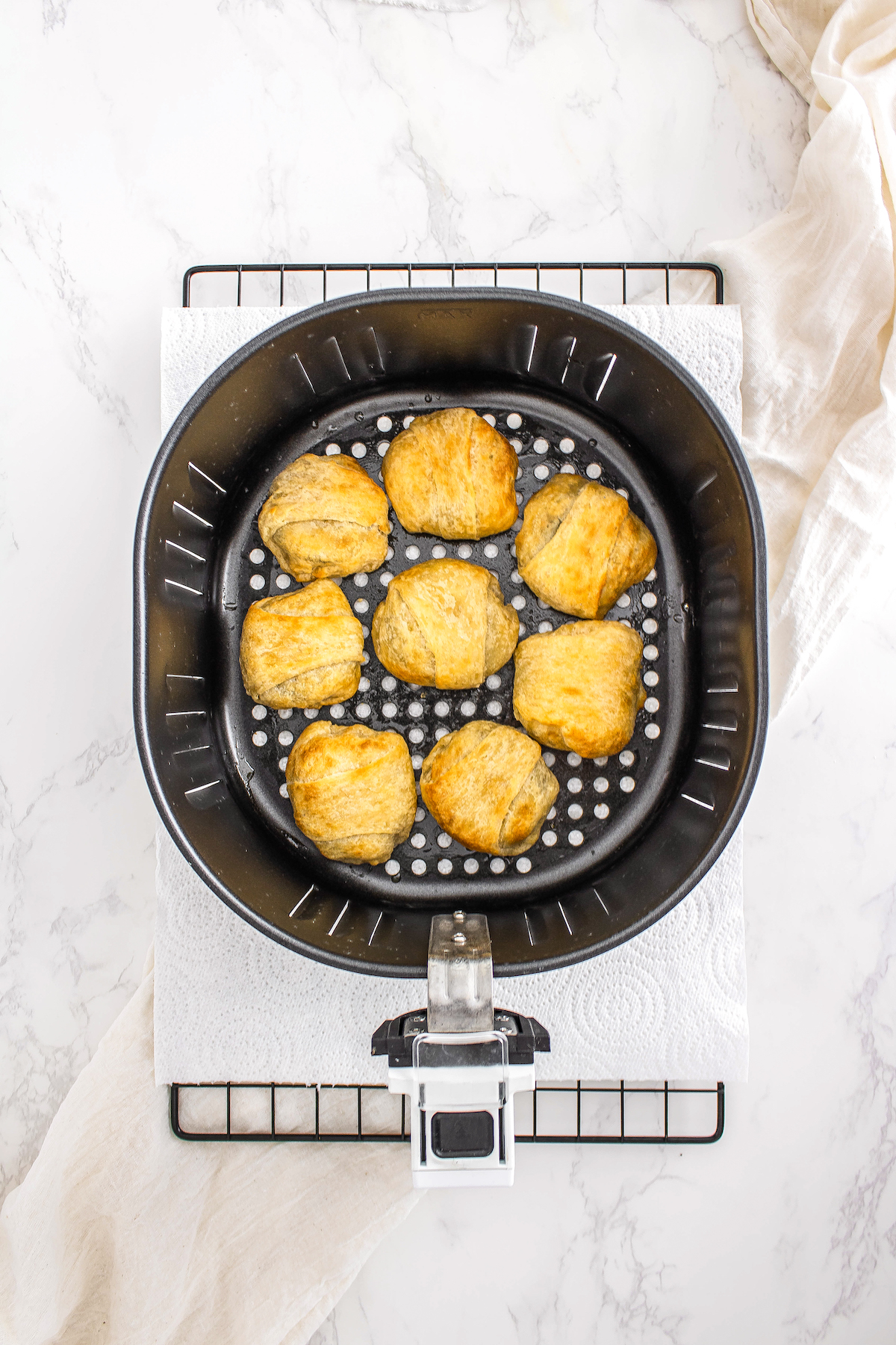 top view of an air fryer with eight crescent roll-wrapped Oreos after cooking