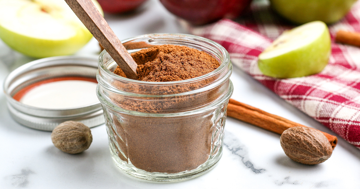 A very small mason jar filled with golden-brown spices and a tiny wooden spoon.