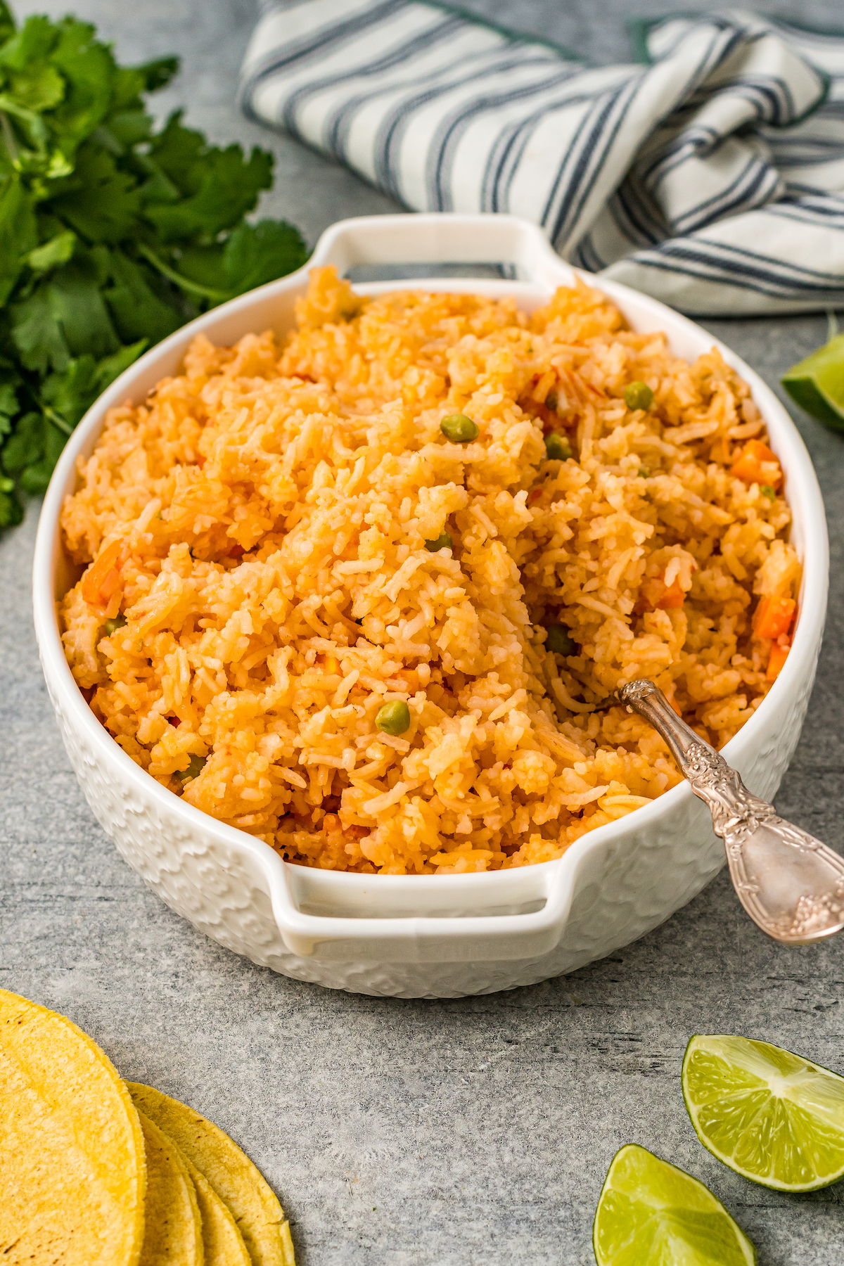 A casserole dish filled with seasoned rice. A spoon is stuck into the rice.