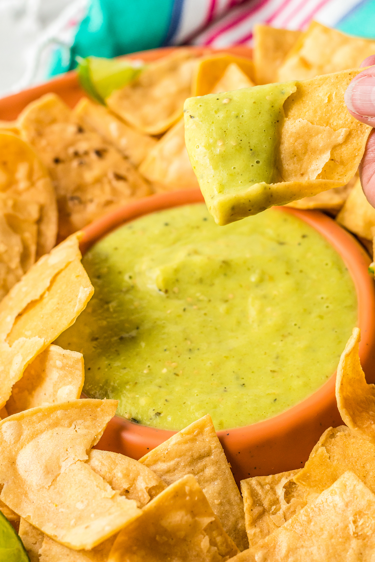 A platter of chips and salsa. One chip has been dipped into the salsa and lifted toward the camera.