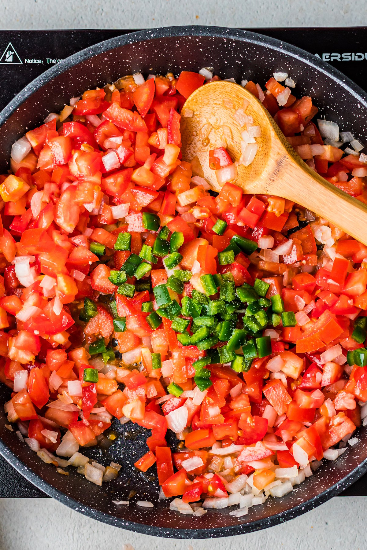Tomatoes, jalapenos, and onion in a skillet.