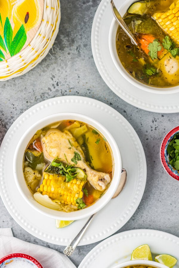 Two bowls of caldo de pollo with lime wedges on the side.