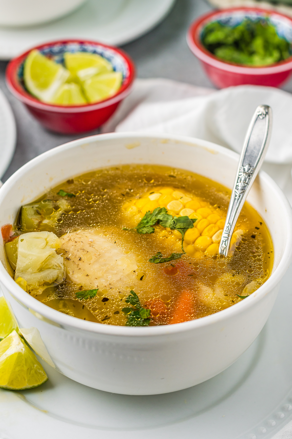 a bowl of Mexican soup with a chicken leg, corn, and other vegetables in a rich broth
