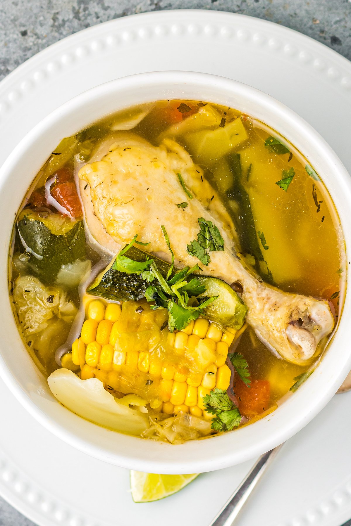 a bowl of Mexican soup with a chicken leg, corn, and other vegetables in a rich broth