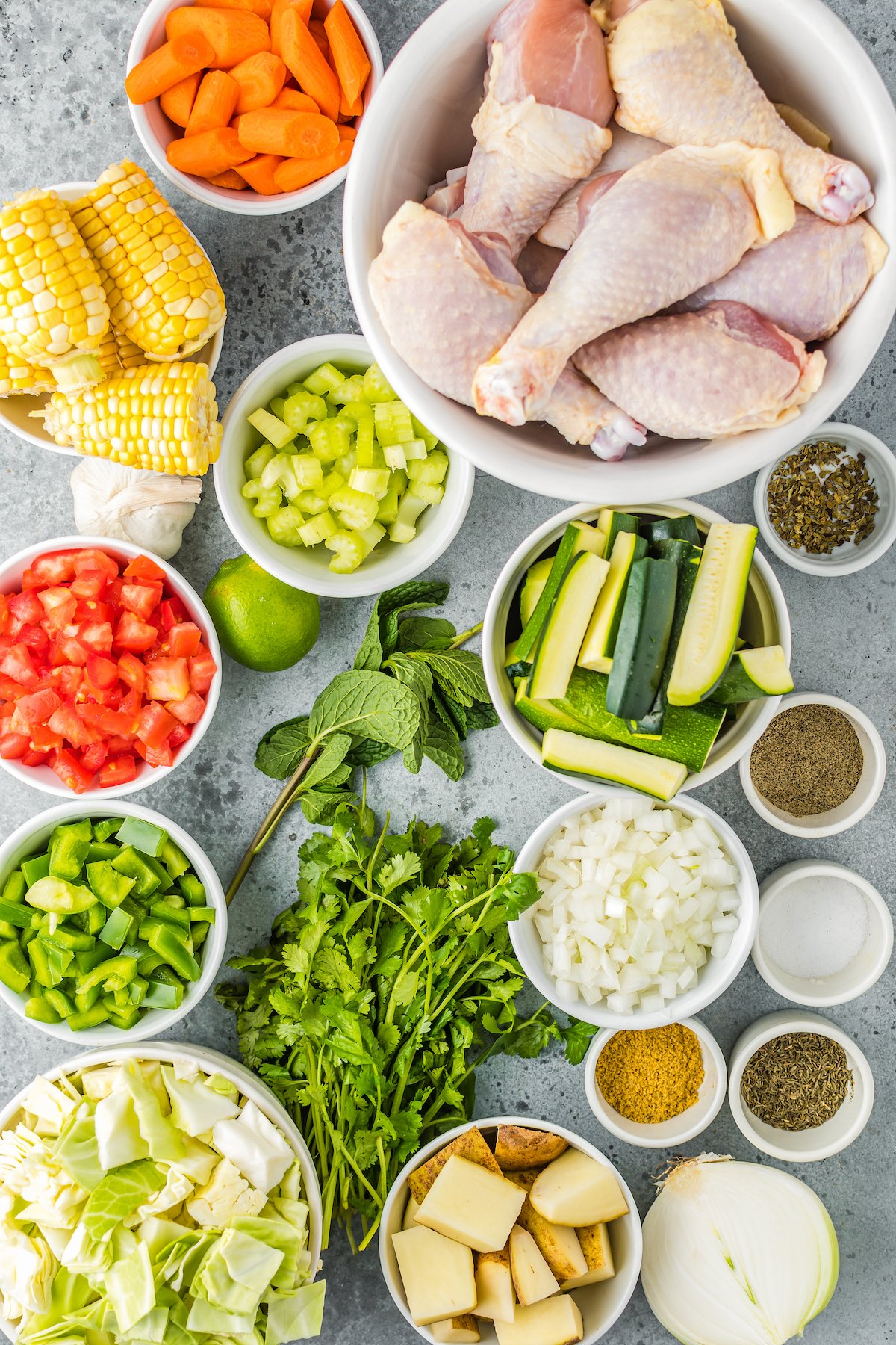 All of the ingredients to make Caldo de Pollo incuding chicken, vegetables, and herbs