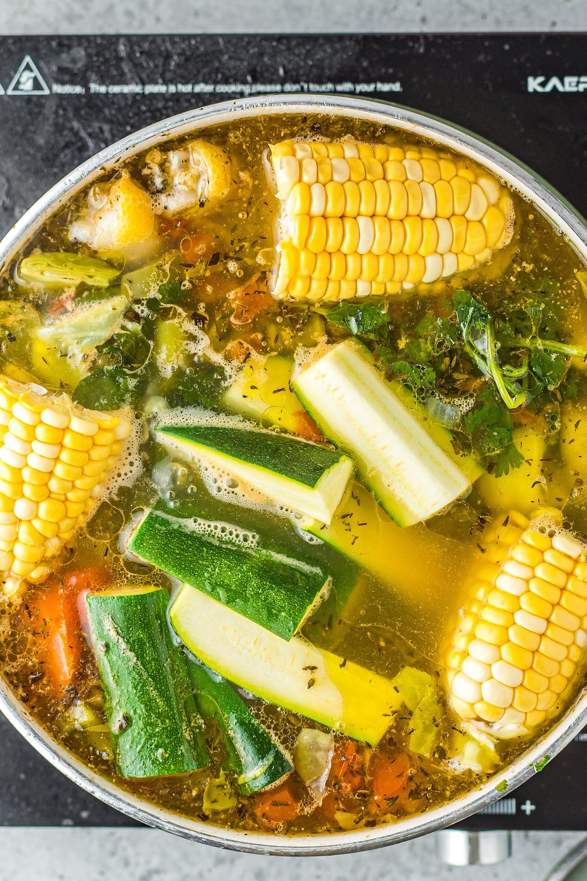 chicken, corn, potatoes, and fresh herbs in a stockpot